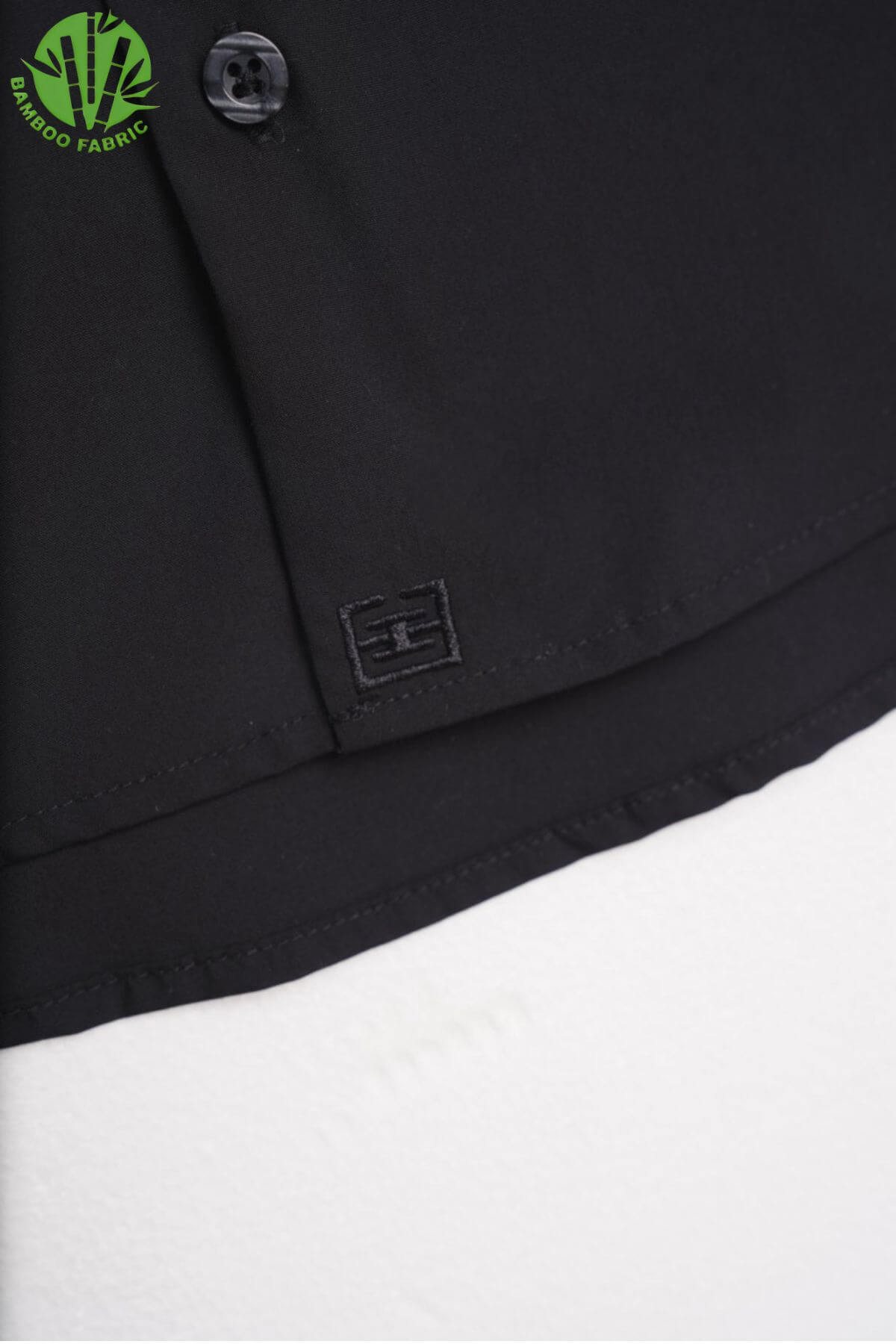 Bottom logo detail of men’s black bamboo Riviera long sleeve shirt – subtle branding with refined finishing on sustainable fabric
