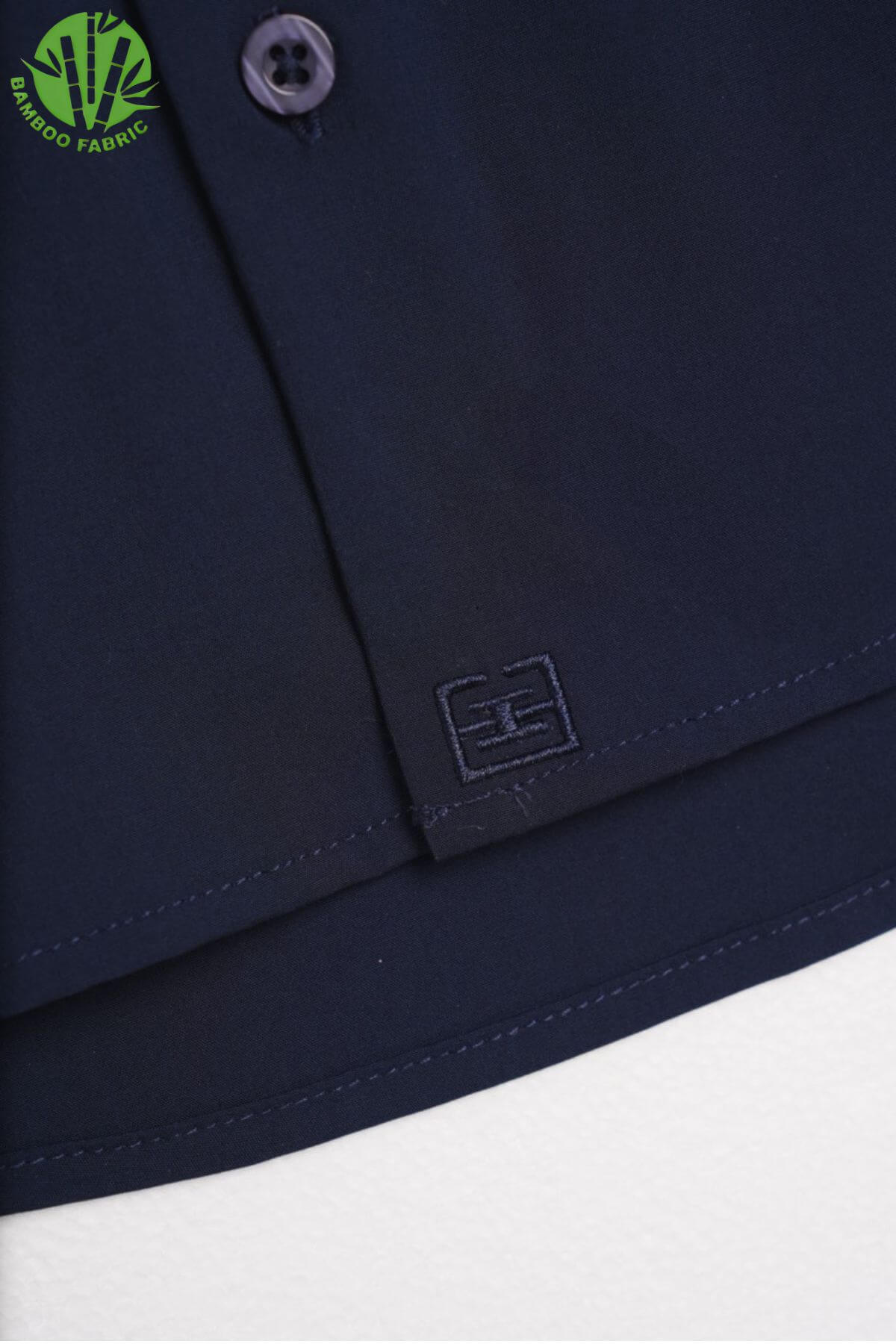Close-up of the bottom logo detail on men’s navy bamboo Riviera long sleeve shirt – subtle branding with refined finishing.