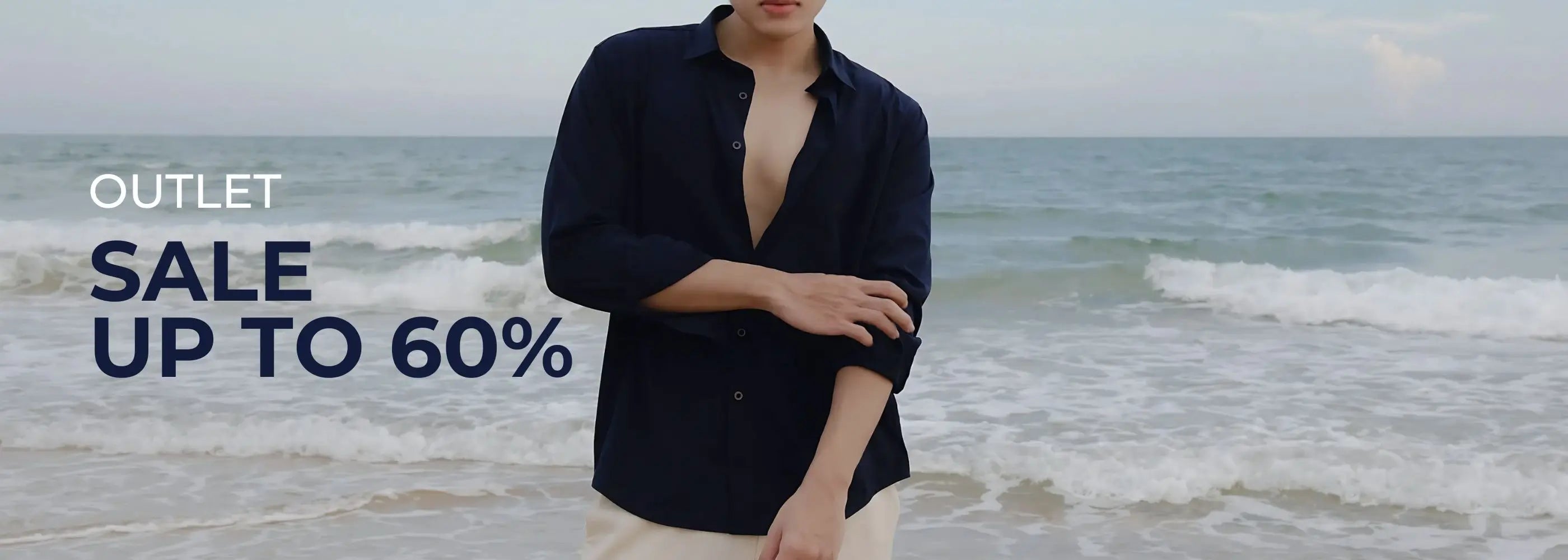 Person wearing a navy shirt on a beach with an outlet sale banner.
