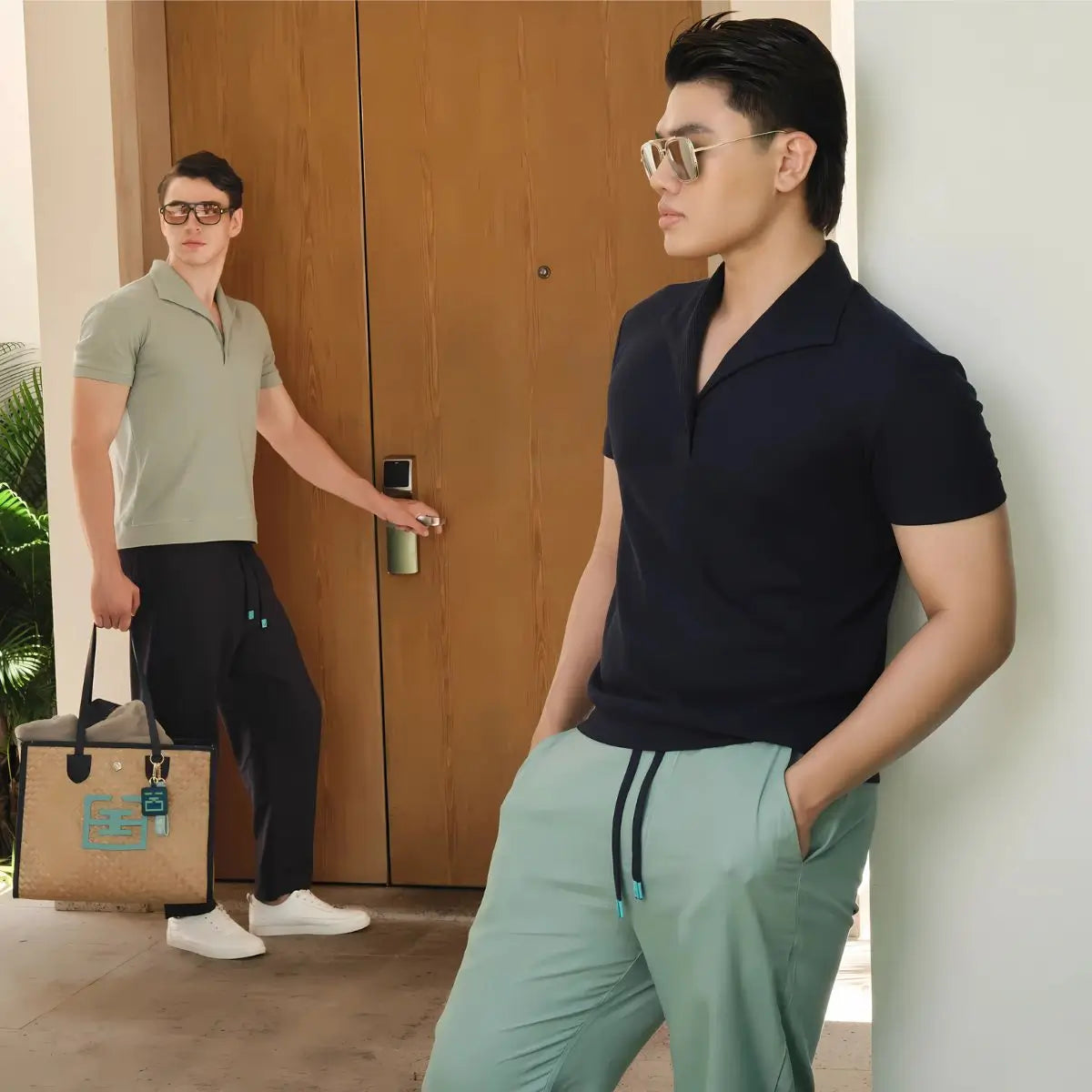 Two men in stylish outfits standing near a wooden door.